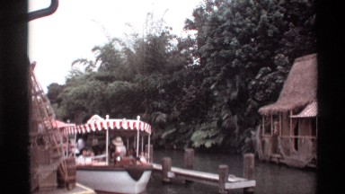 1974: people sit on a novelty river boat with a read and white striped canopy.