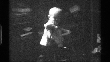1976: a baby in a bib frolics with a microphone indoors. KENTUCKY
