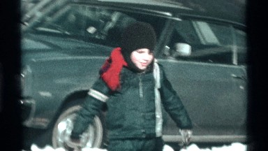 1971: Little Boy Wearing Snowsuit Jumps and Slides Down Snow Pile