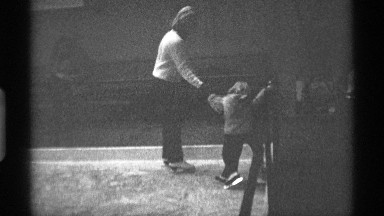1971: mother with two children balancing and learning to ski at indoor ski area.