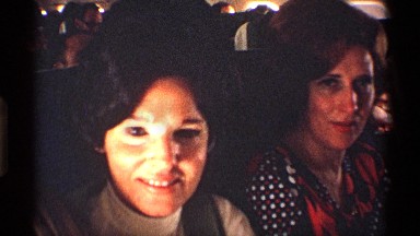 1971: people sitting in rows on a plane, the people in front interacting