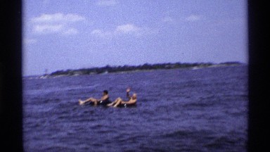 1971: two man ocean center place sit in the rubber tube very happy morning time