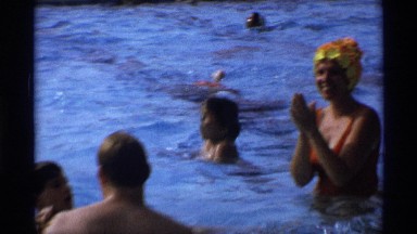 1971: the people are enjoying in the swimming pool and the man take his child