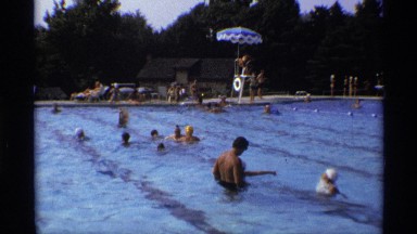 1971: a busy scene of a community pool on a sunny day, zooming in