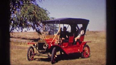 1969: kids playing in an old fashioned red car by the sunny hot fields JORDAN