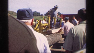 1969: man riding on a machine that is used to cut lumber
