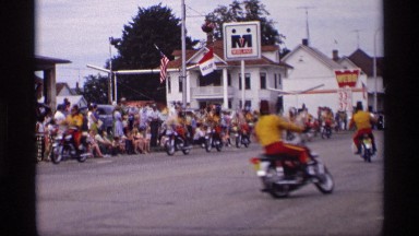 1969: many people riding motorcycles in a circle in the middle of the road