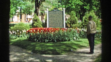 1969: an older man stands with his hands in his pockets and looks at a memorial