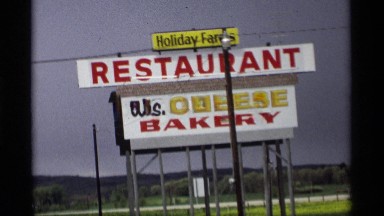 1969: a statue at the top of a building and a board that represent a bakery shop