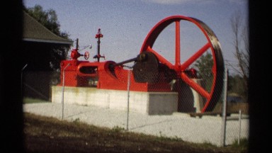 1969: man walking up to inactive large red watering wheel with pipes HOLLAND