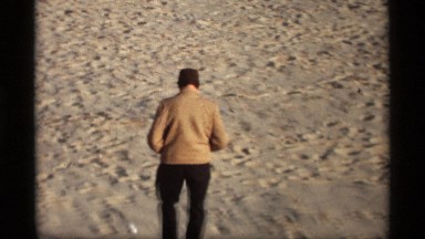 1969: a middle aged man walking all alone on a sand filled path on a hot sunny