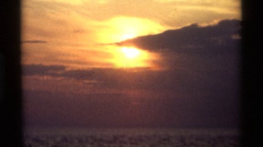 1969: beautiful colorful sunset seen through the clouds out over the ocean