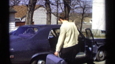 1966: a person taking luggage bag and hat from his car at morning time MADISON