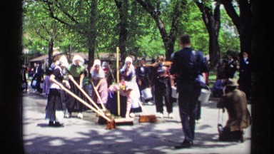 1969: ladies are cleaning the road with broom and a man taking that event