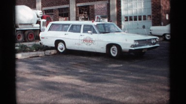 1969: white wagon car parked beside an office building on a shiny day HOLLAND
