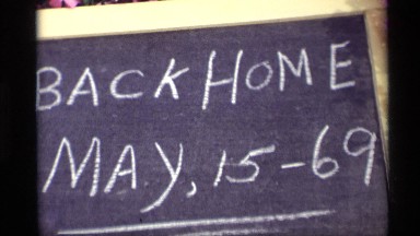 1969: a blackboard displaying "back home may, 15-69" in white chalk HOLLAND