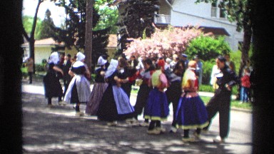 1969: a women dance in our stage people watch the dance near to tree building