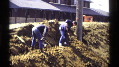 1969: men digging a path in the dirt next to a canal