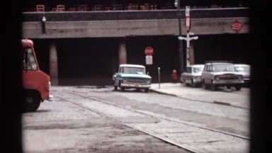 1969: street view of an intersection with tracks running beside a overpass