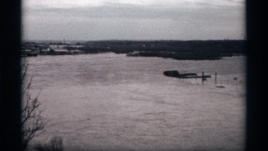 1969: open area sandy land with trees and distant view near a residential area