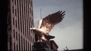 1969: the eagle fly statue yellow color near to big building and wall morning