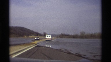 1969: wet roadway covered with water due to possible flooding in the countryside