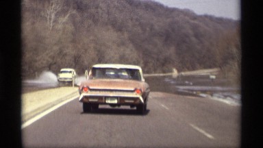 1969: flooded highway beside a highland area with water over the roads and car