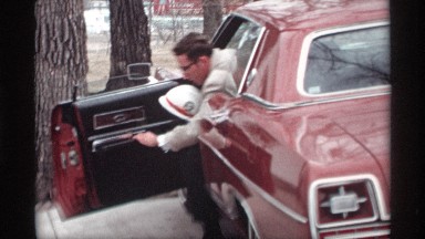 1969: man opens driver's side car door and steps out carrying white hard hat