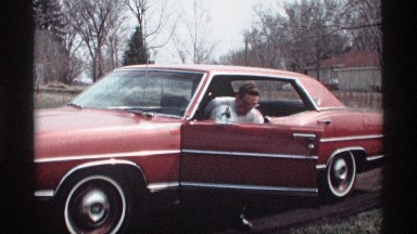 1969: man get out of car then puts on a hard hat. SAVAGE MINNESOTA