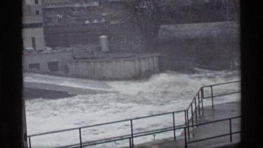 1969: rainy day storm floods a river with rapid river currents overflowing