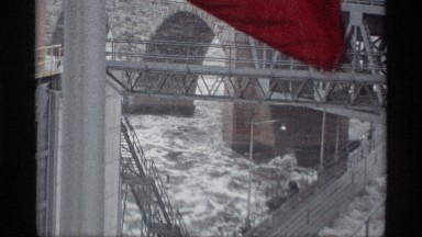 1969: view of the base of a bridge with water sloshing around and a flag