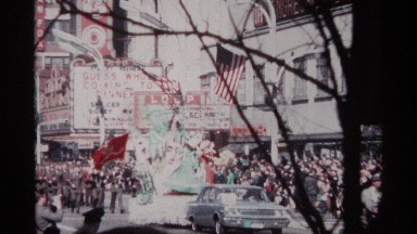 1968: a large group of people walking in the middle of a street behind a car