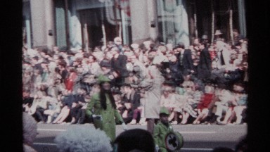 1968: at a festival a lady with dog follows a small boy who is having drums and
