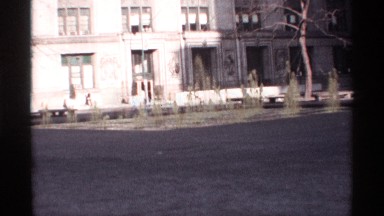 1968: a woman walks past a beautiful building with playful water fountains on a