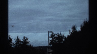 1974: pine tree lined road as the car travels toward tall bridge SEATLLE
