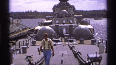 1974: tourist walking on top of a giant retired naval ship at the port docks