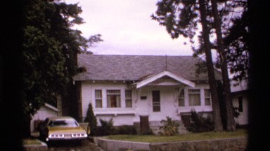 1974: Scene from the Past - Car Parked Next to House While Vehicles Drive Down Street