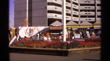 1974: a crowd of people on a sunny day downtown meandering along WORLDS FAIR