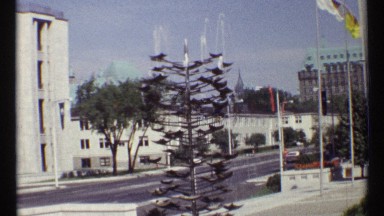 1967: a road and more buildings are surrounding some people are walking there a
