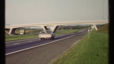 1967: a highway road and a bridge also there car and vehicles are moving fast at