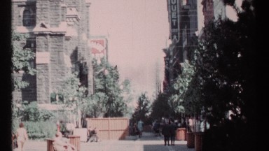 1967: Daytime Car Passing in Busy City Center with Buildings Around