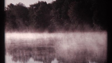 1967: calm and clear water of the small river amid a bushy land with beautiful