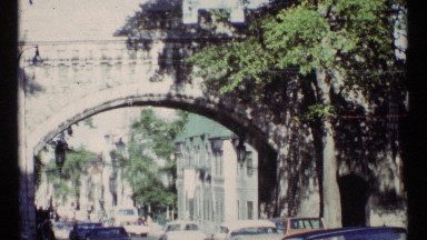 1967: many vehicles are passing through under a bridge in a sizable town OTTAWA