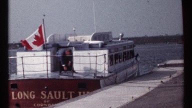 1967: canadian boat long sault iii docked on lake with man opening hatch