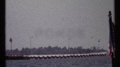 1967: a river and a milestone also there a flag at the post stick and some trees