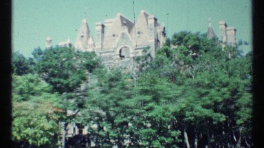 1967: building with triangle forms and building with turret tower over trees