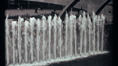 1967: fountain at the open place and people are walking and an arch also there