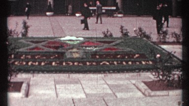 1967: a low number of people walk on the stone flooring outside in the warm