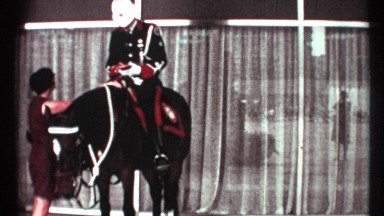 1967: finely suited officer on a black horse talking to a lady and man passing