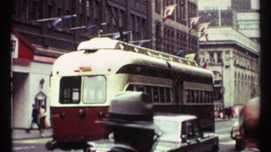 1967: in a big city old model tram, and car are travelling in the road so many